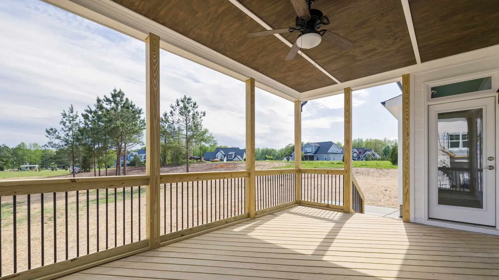 Covered porch with a ceiling fan, fresh wood decking and a view of open lawn