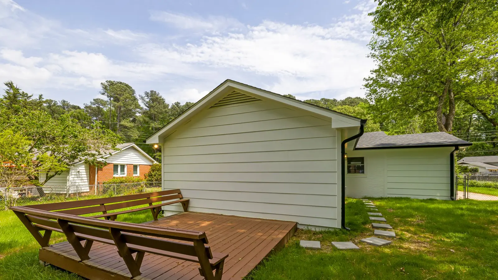 Low wood platform deck with built-in benches in a grassy backyard