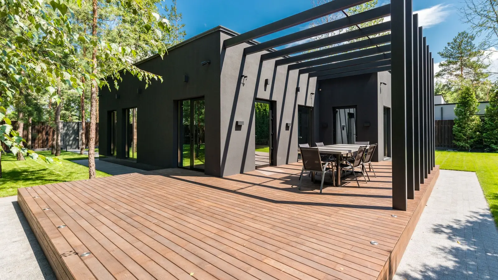 Modern wood deck with a black pergola frame and an outdoor dining table