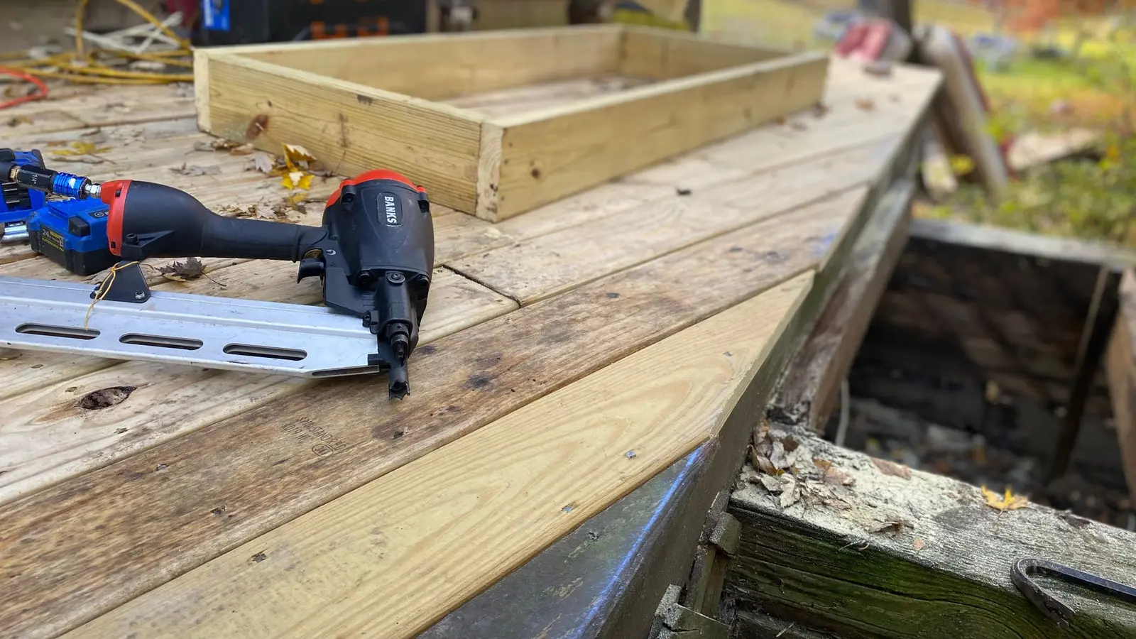 Nail gun and new lumber on a deck frame under construction