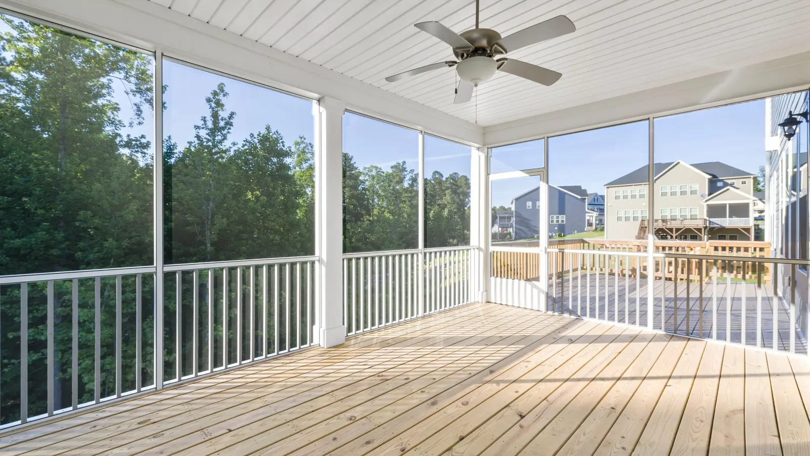 Bright screened porch with white railings and a ceiling fan